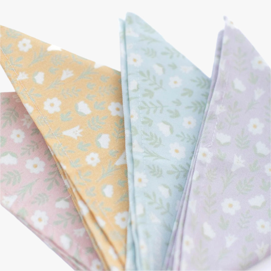 all four color variants of the table napkin in light pink, light blue, light yellow and light lilac folded on a white background.