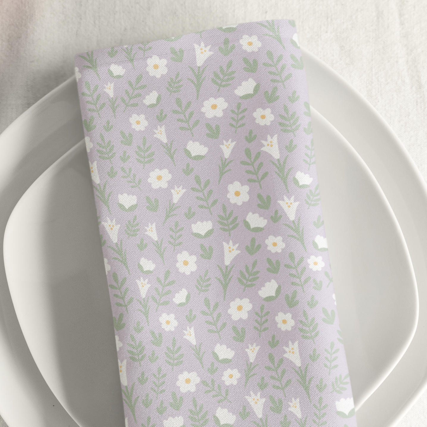 Light lilac Easter Alleluia napkin with white floral design placed on a plate in a styled table setting.