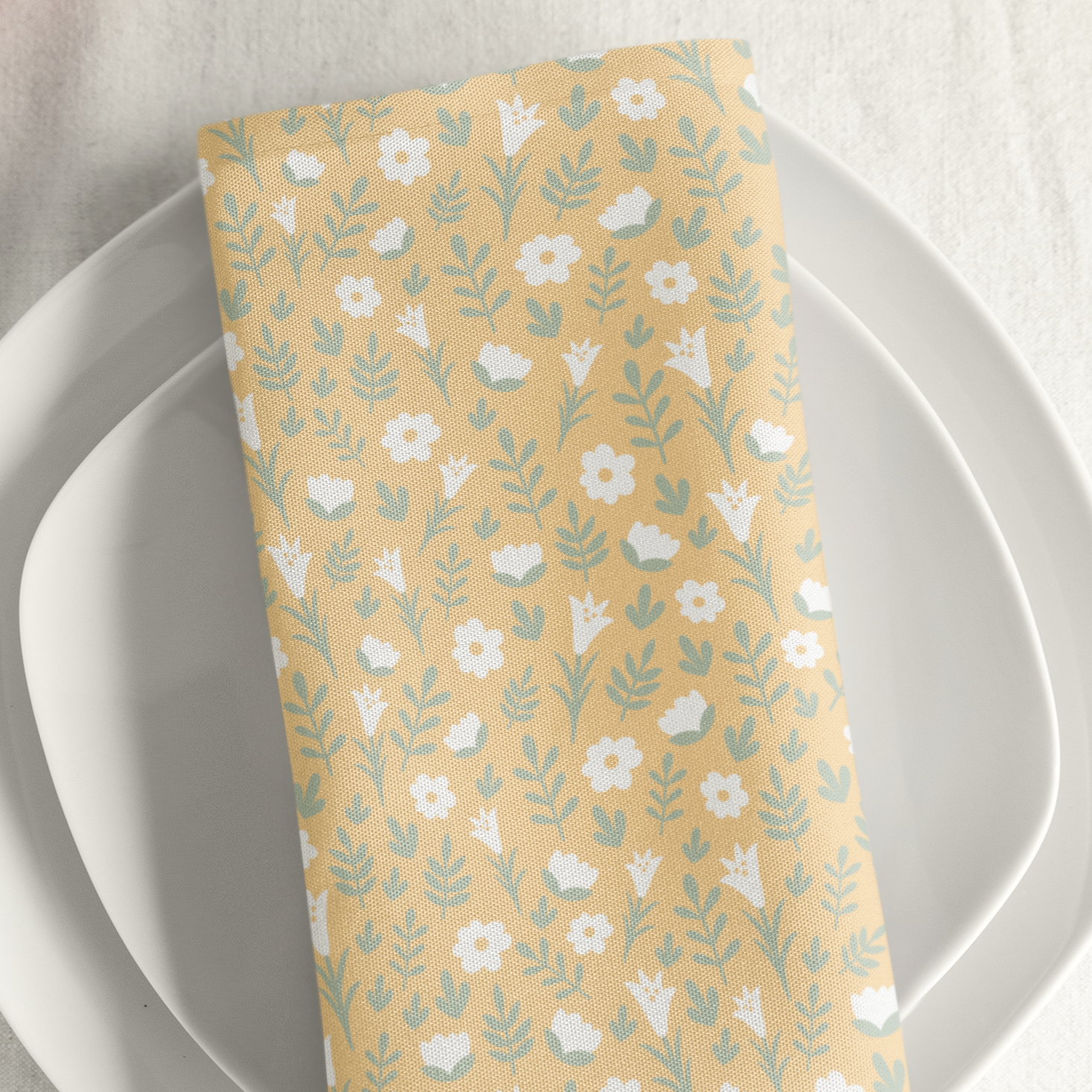 Yellow Easter Alleluia napkin with white flowers placed on a plate in a styled table setting.