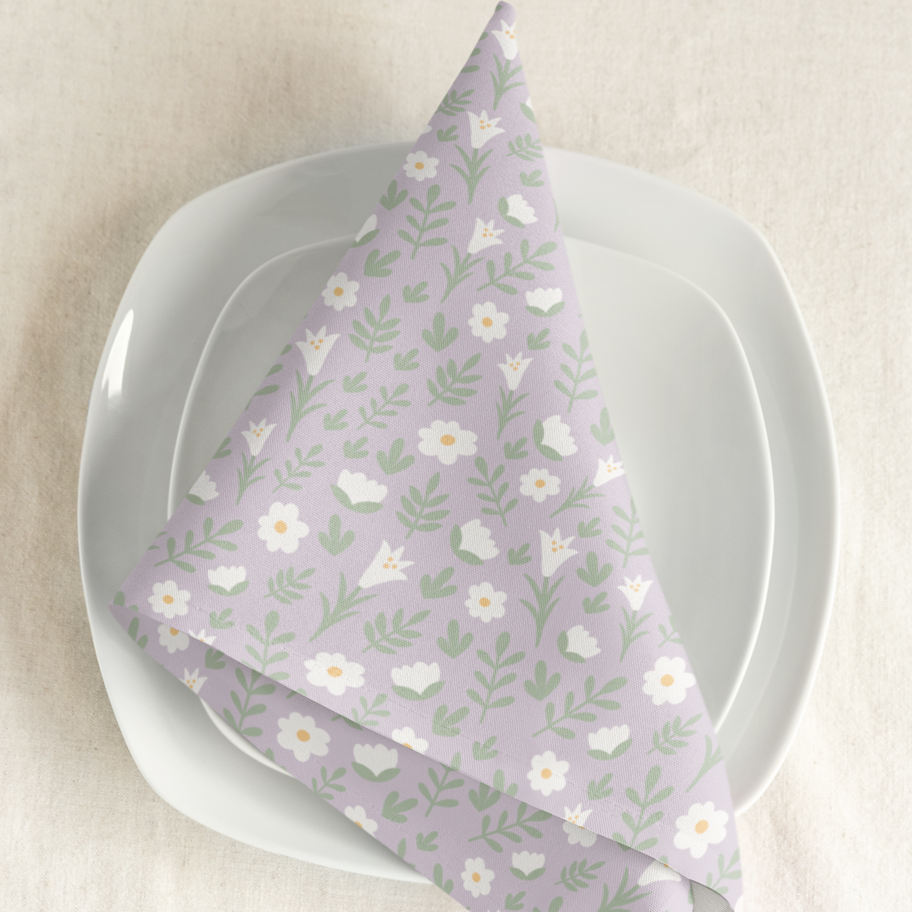 Light lilac Easter Alleluia napkin with white floral design placed on a plate in a styled table setting.