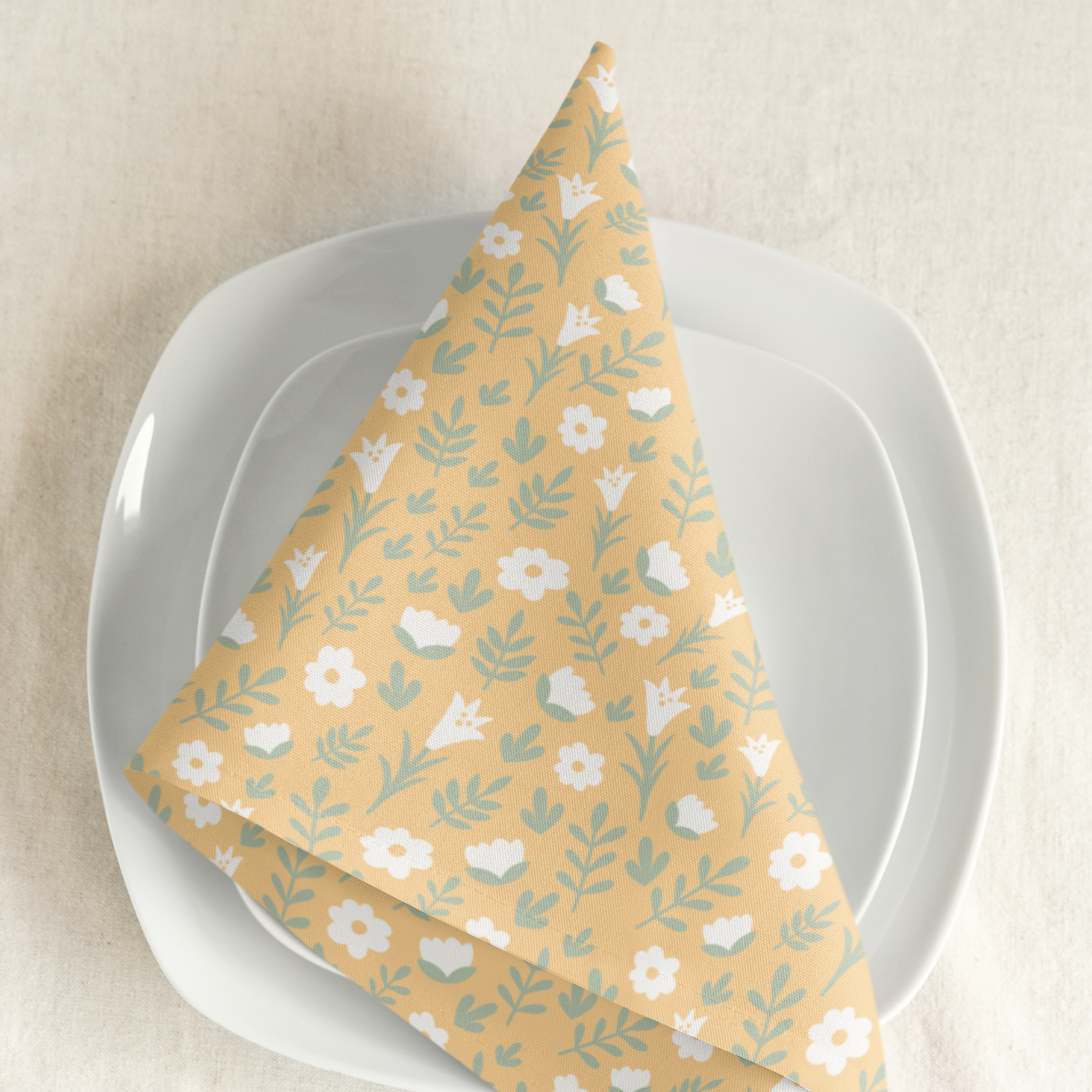 Light yellow Easter Alleluia napkin with white floral design placed on a plate in a styled table setting.
