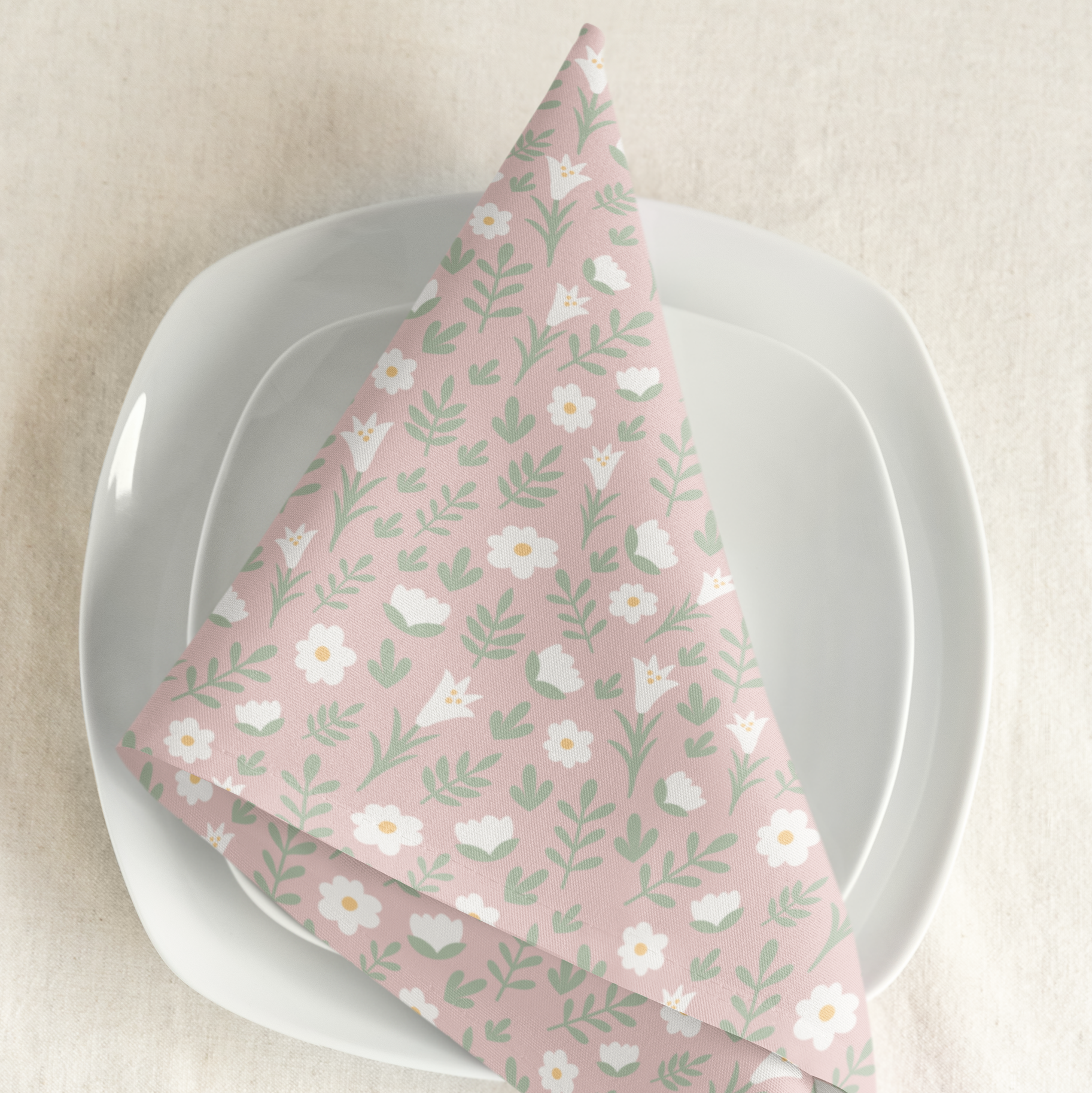Light pink Easter Alleluia napkin with white floral design placed on a plate in a styled table setting.