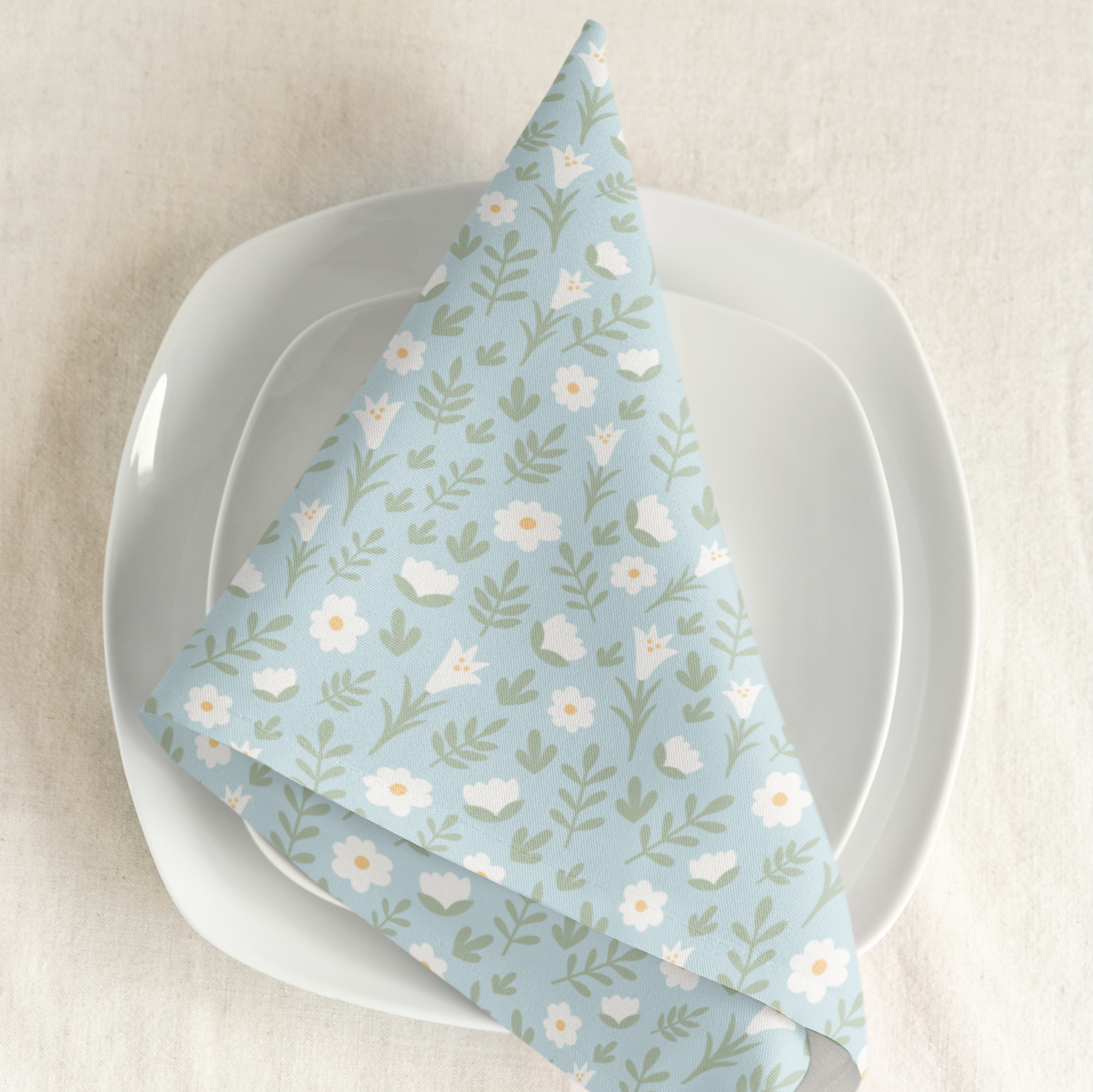 Light blue Easter Alleluia napkin with white floral design placed on a plate in a styled table setting.